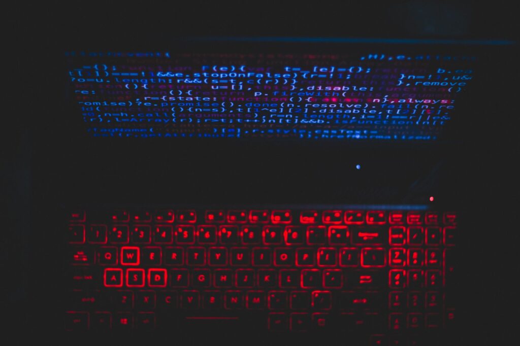 Écran de code sur un poste de travail éclairé en rouge, illustrant une attaque informatique en cours